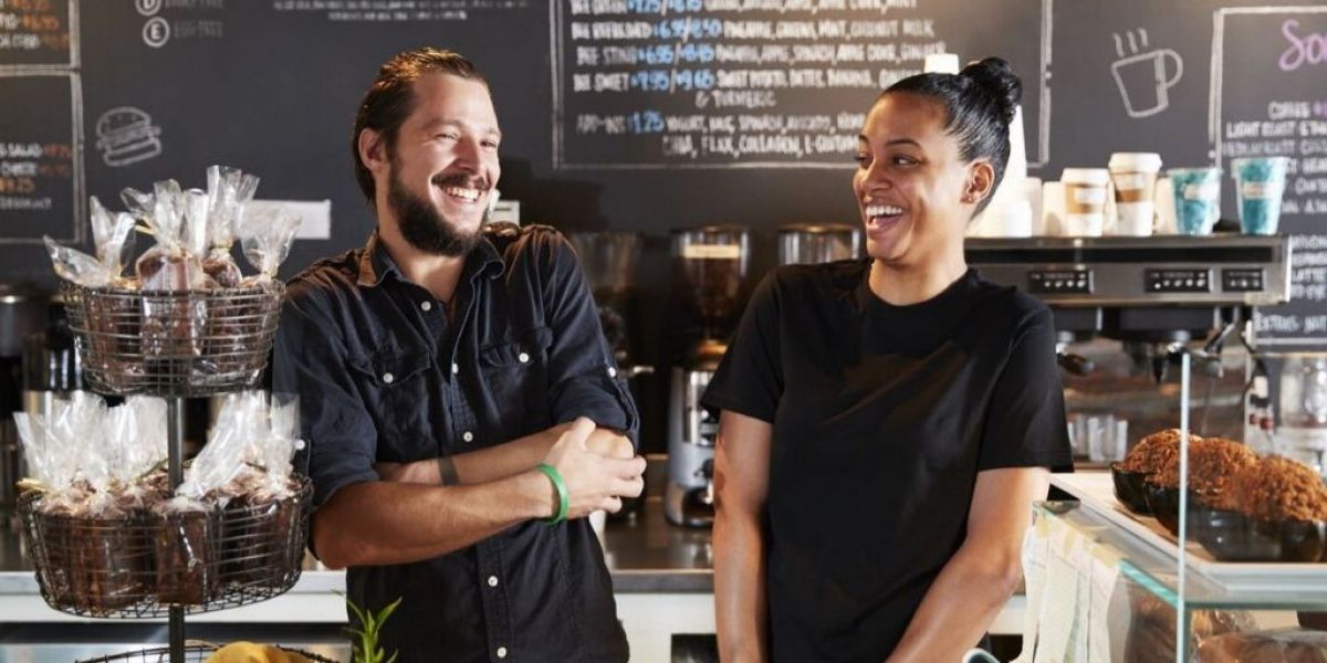 Image of two social entrepreneurs smile in their social enterprise coffee shop