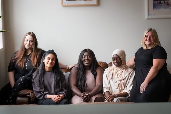 Group of women sitting on a sofa, smiling at the camera